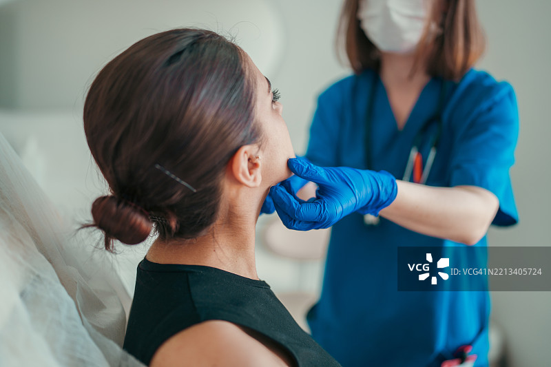 医生用戴手套的手检查病人的喉咙或甲状腺图片素材