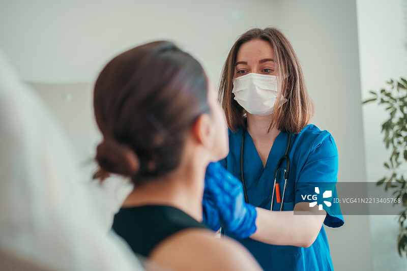 医生用戴手套的手检查病人的喉咙或甲状腺图片素材
