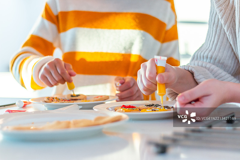 快乐的多元文化少女在家里的厨房装饰饼干图片素材