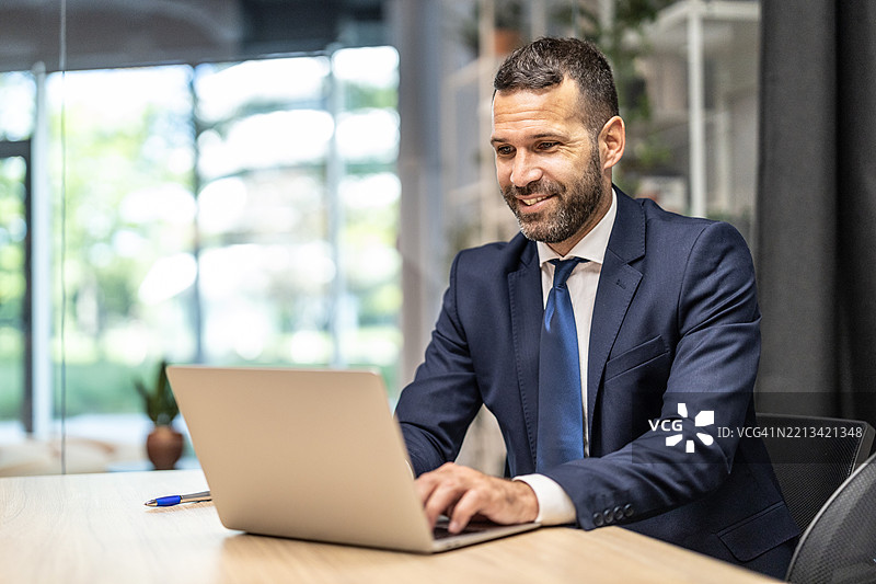 专注于笔记本电脑的商人在现代办公室环境中图片素材