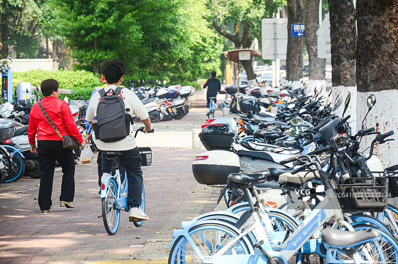 人们在 sidewalk 上骑共享单车。图片素材