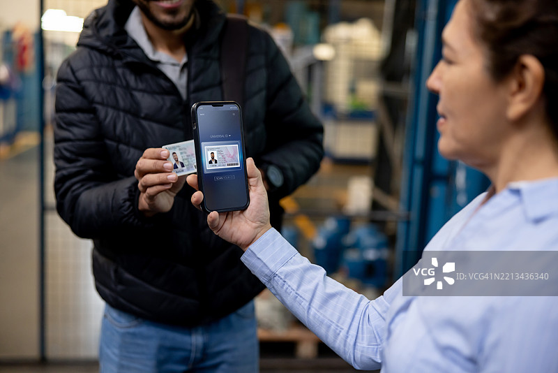 主管在门口扫描仓库工人的身份证件图片素材