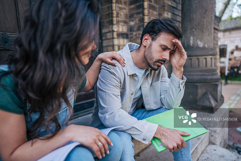 年轻女性在户外安慰伤心的大学生图片素材