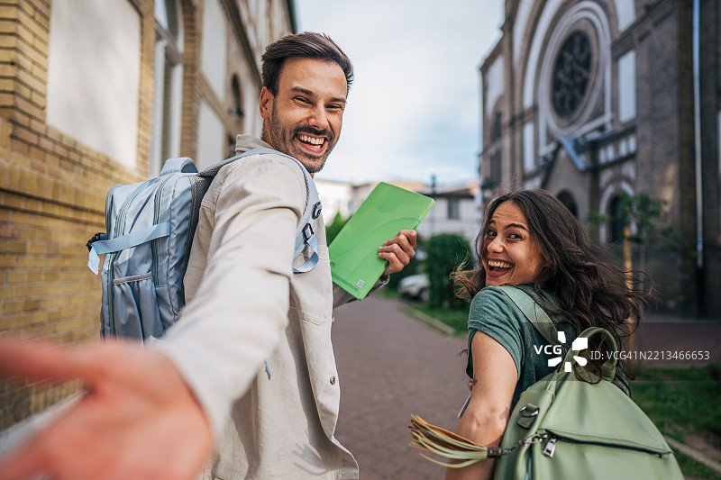 快乐的学生在大学校园里手牵手走着图片素材