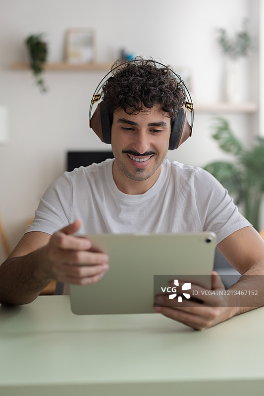 年轻男子在家中观看平板电脑上的视频图片素材