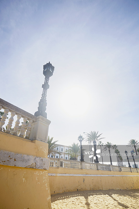 低角度视图的老式街灯，背景是黄色涂漆的墙壁和天空与阳光。图片素材