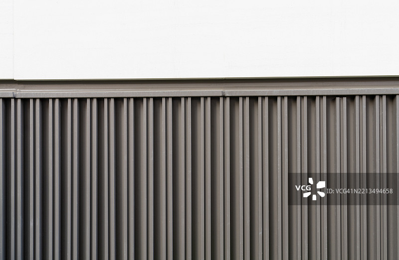 灰色金属围栏面板靠在白色墙壁上图片素材
