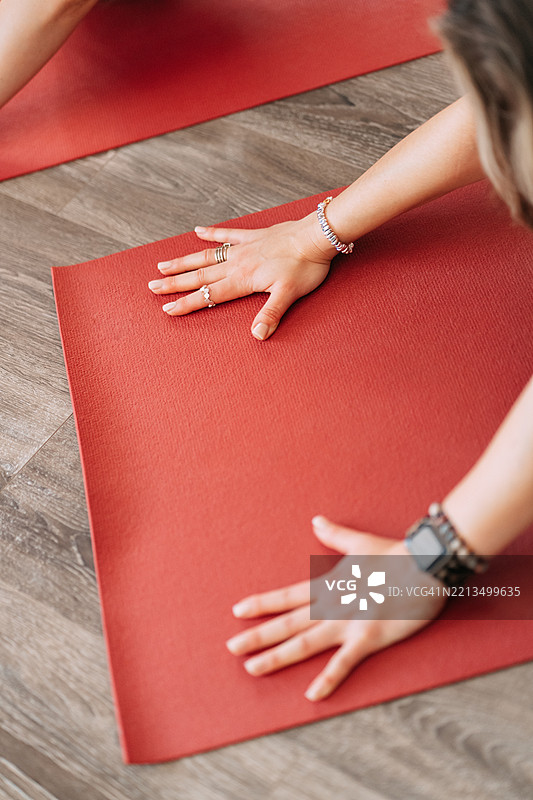 女人在红色瑜伽垫上做瑜伽：双手放在地面上图片素材