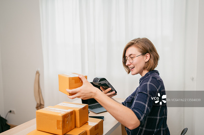 年轻女商人正在扫描包裹以便发货图片素材
