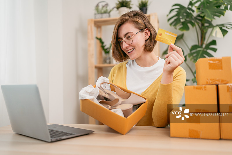 年轻女性在家享受在线鞋子购物图片素材
