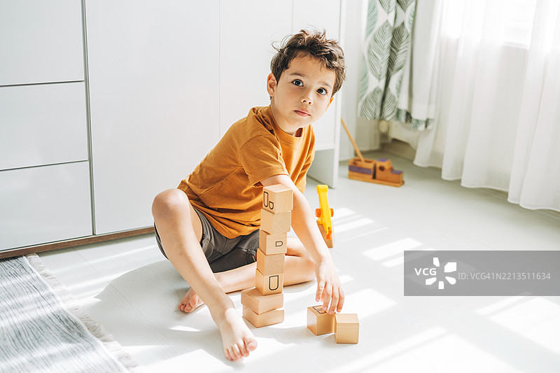 小男孩在玩耍时专心致志地搭建木块塔，展现出专注力。快乐的童年图片素材