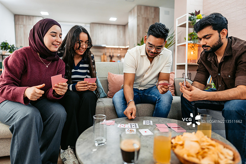 一群印度和穆斯林朋友在沙发上一起玩牌图片素材