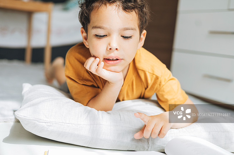 男孩在枕头上专注地阅读，沉浸在宁静的思考时刻。图片素材