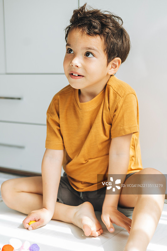 一个年轻男孩坐着，面带好奇和感兴趣的表情仰望。图片素材