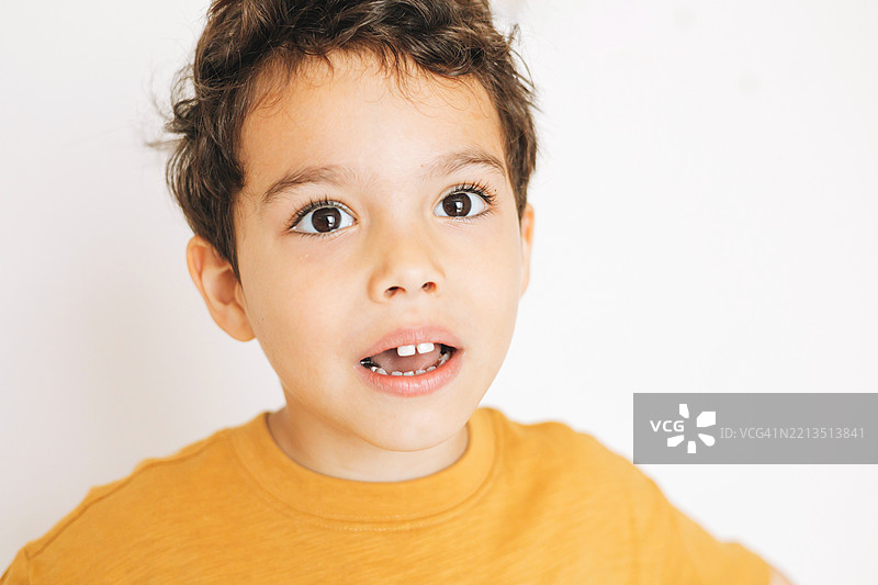 一个迷人的小男孩，眼神丰富，表情好奇，背景为白色。图片素材