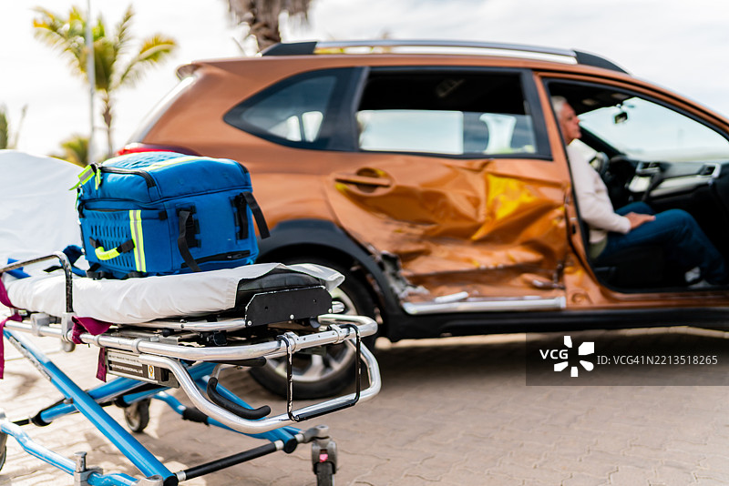 受损汽车旁的急救担架，车内有一位老年男性图片素材