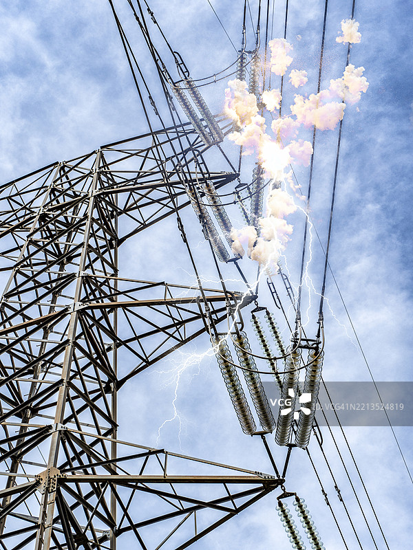 低角度视图，高压电塔上短路引发爆炸，背景是蓝天。图片素材
