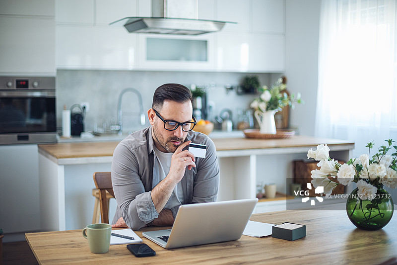 中年男子在现代厨房中网上购物图片素材