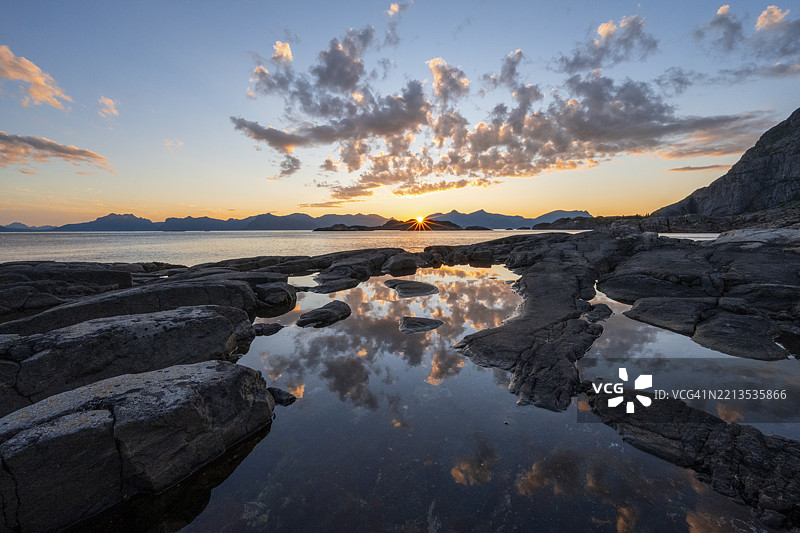 岩石海岸上的小池塘中倒映着云彩，日落时分的海岸风景，赫宁斯维尔，洛福滕群岛，诺尔兰，挪威，欧洲图片素材