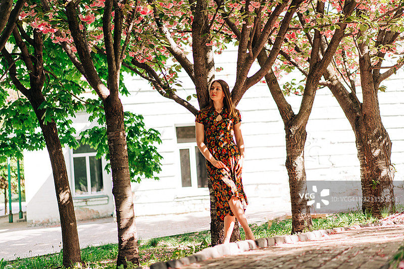 微笑的女性在春天的樱花树旁摆姿势图片素材