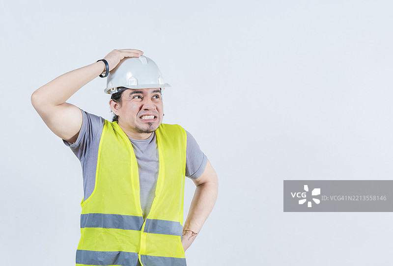 困扰的建筑工人独自捂着头。担忧的建筑工程师捂着头。烦恼的年轻工程师捂着头。图片素材