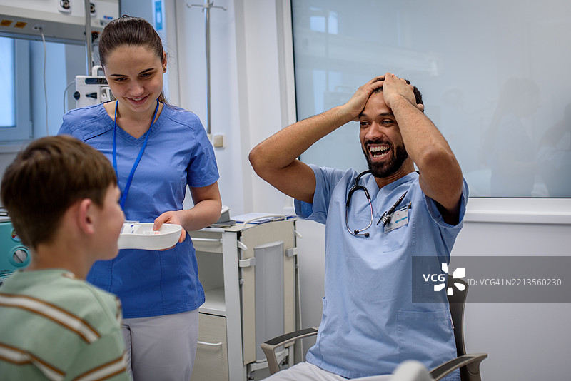 快乐的医生与儿科病人和护士一起庆祝好消息。图片素材