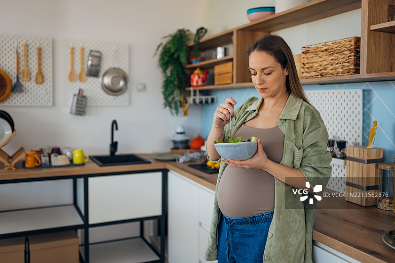 一位孕妇在厨房享用富含维生素和矿物质的健康有机沙拉作为早餐图片素材