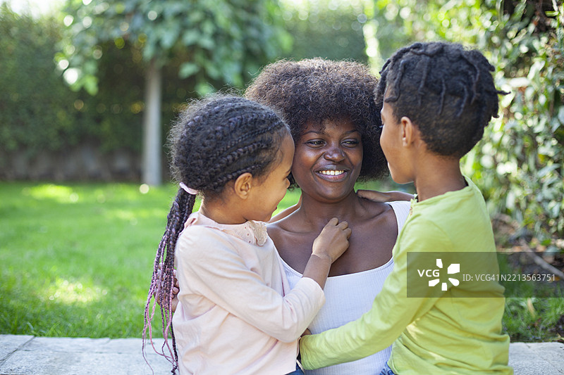 快乐的非洲母亲在后院里抱着儿子和女儿，他们正在玩耍。图片素材