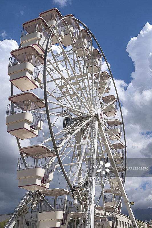 一个大型摩天轮，前面有许多舱室，背景是部分多云的蓝天，阿尔巴尼亚，地拉那，欧洲图片素材