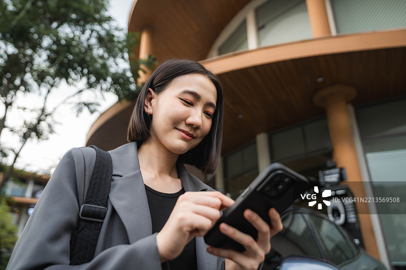 一位自信的女性走出她的电动车，顺利地关上车门。图片素材
