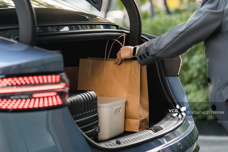 一位女性正在从电动车的前备厢中取物品图片素材