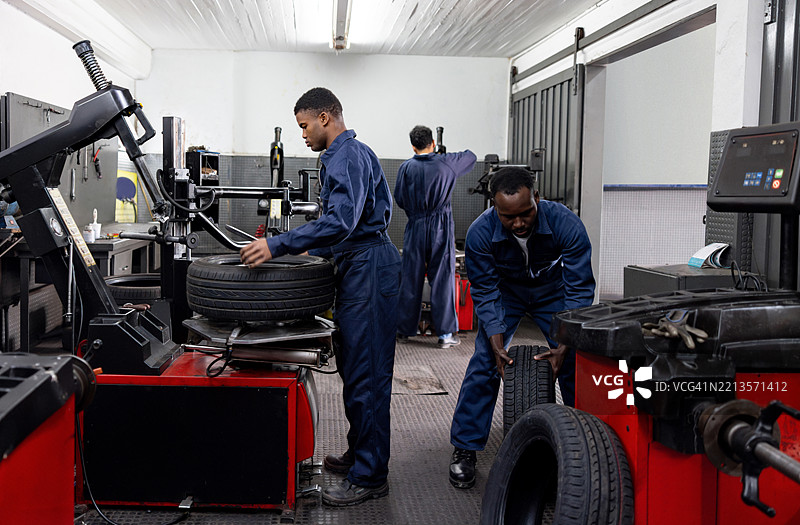 机械师在汽车修理厂修理漏气轮胎图片素材