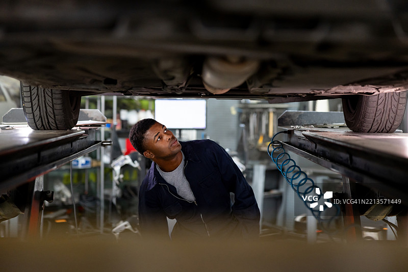 机械师在用千斤顶抬起的车辆下检查。图片素材