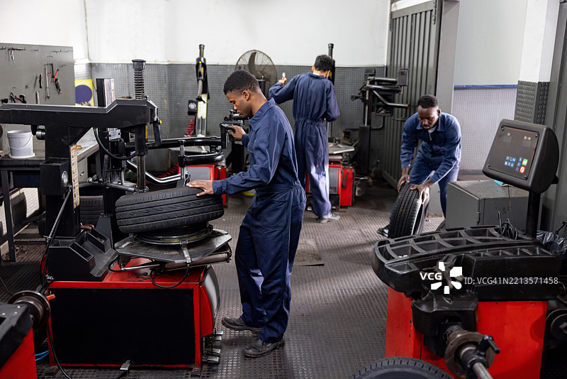 在汽车修理店工作的机械师修理漏气轮胎图片素材