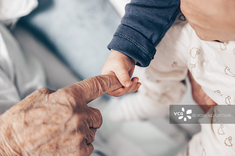 生命的轮回，小男孩的手握着曾祖母皱纹的手指图片素材
