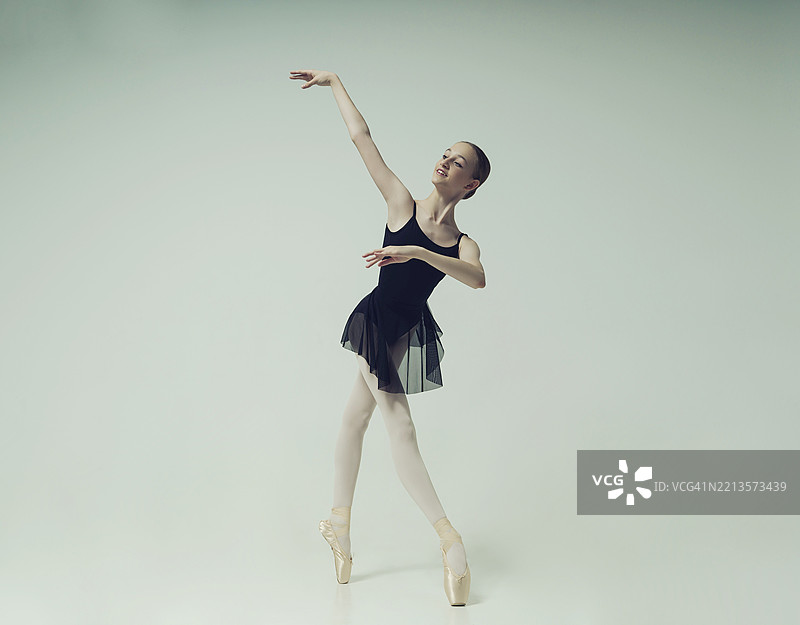 年轻的青少年芭蕾舞者在摄影棚中摆姿势，展示芭蕾舞和舞蹈动作图片素材