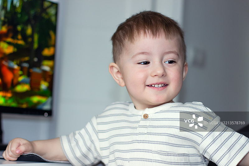 一个两岁小孩的肖像，棕色眼睛，孩子展现出愉悦的情感。图片素材