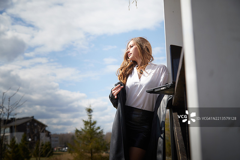 年轻女性在建筑物附近享受阳光明媚的户外时光图片素材