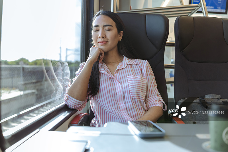 女人在柔和的自然光下享受并在火车旅行中睡觉图片素材