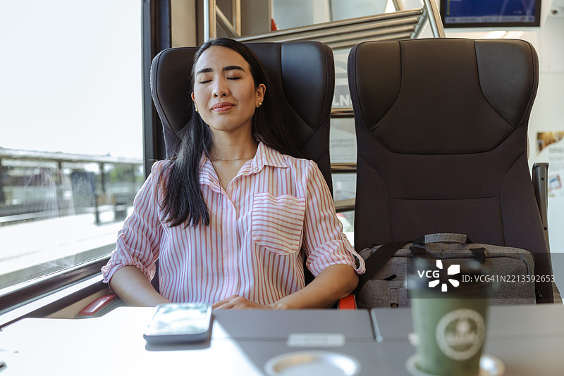 女人在柔和的自然光下享受并在火车旅行中睡觉图片素材