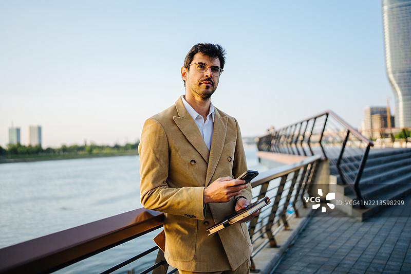 年轻的职业男性在河边拿着平板电脑图片素材
