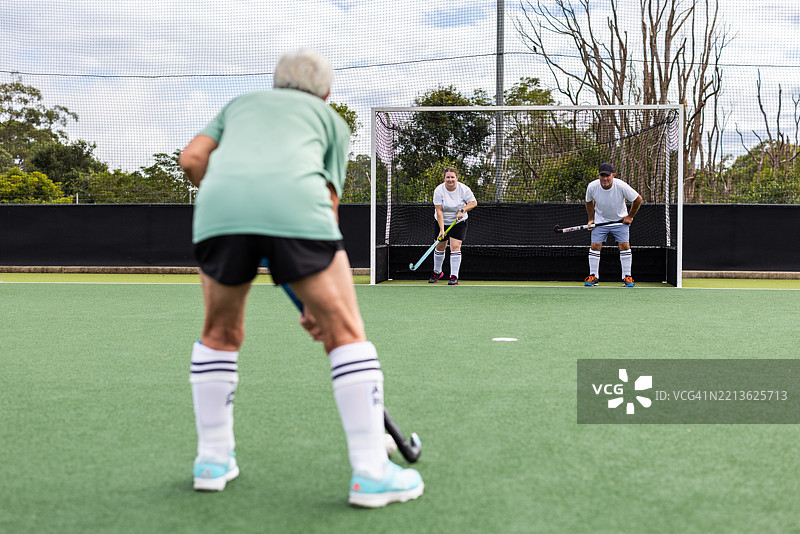 资深女性曲棍球运动员和队友在球门前图片素材