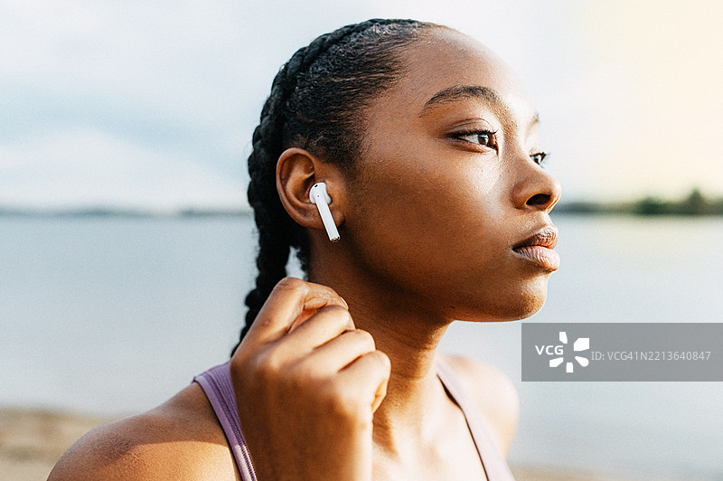 一位年轻女性正在调整她的无线耳塞图片素材