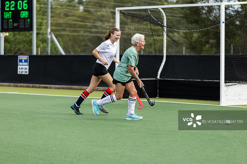 年长女性和年轻女性曲棍球运动员享受争夺球权的乐趣图片素材