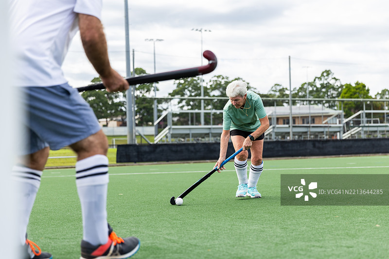 男性曲棍球运动员与一名资深女性运动员争夺球权图片素材
