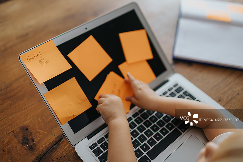 小男孩在笔记本电脑上贴便条图片素材