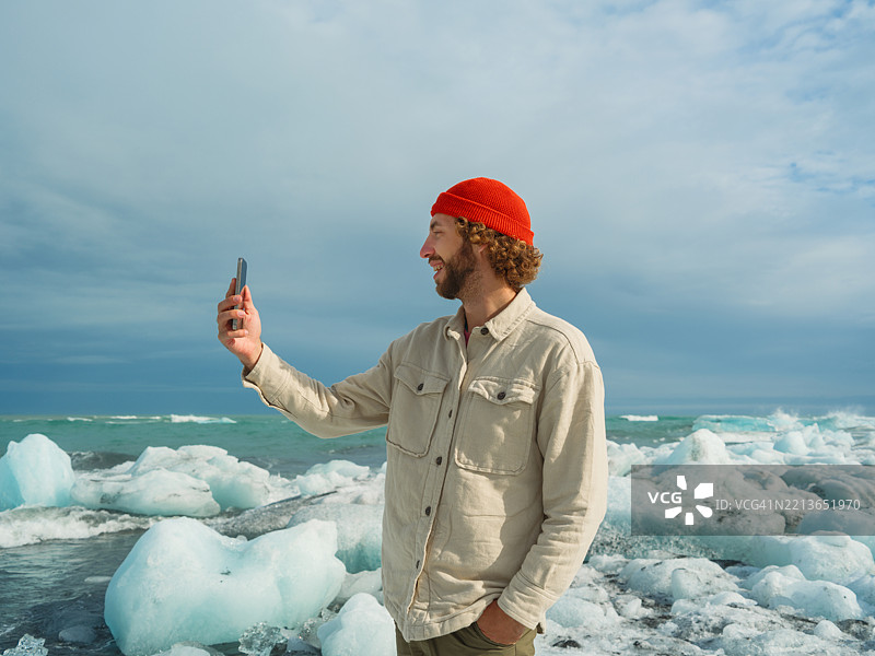 在冰岛钻石海滩用智能手机拍照的男子图片素材