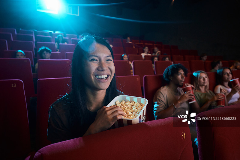 快乐的亚洲女性在电影院观看电影。图片素材