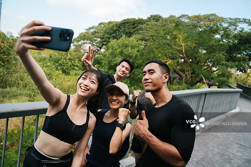 一群充满活力的跑者齐心协力地慢跑，他们的俱乐部领袖在旁边跑着，手持相机捕捉这一瞬间。图片素材