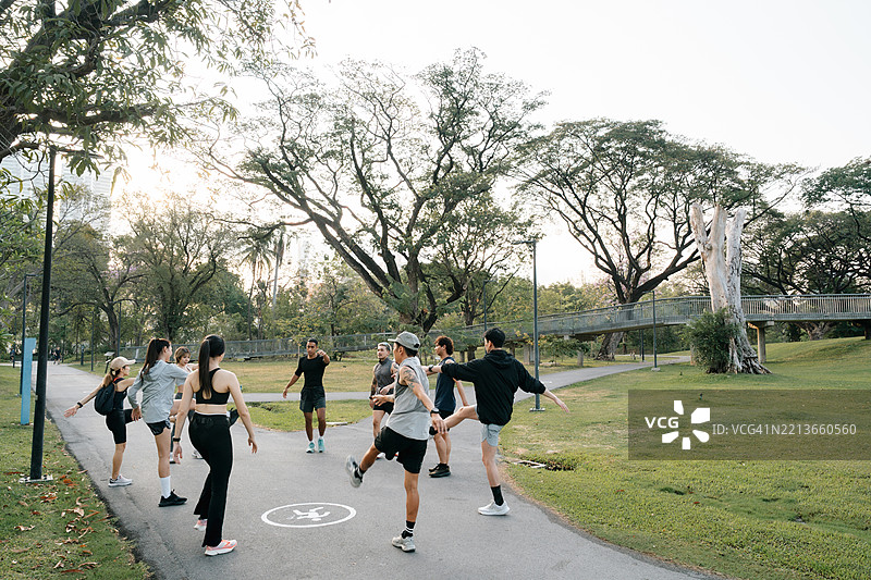 一群跑步者围成一圈，跟随他们的俱乐部教练一起拉伸和热身。图片素材